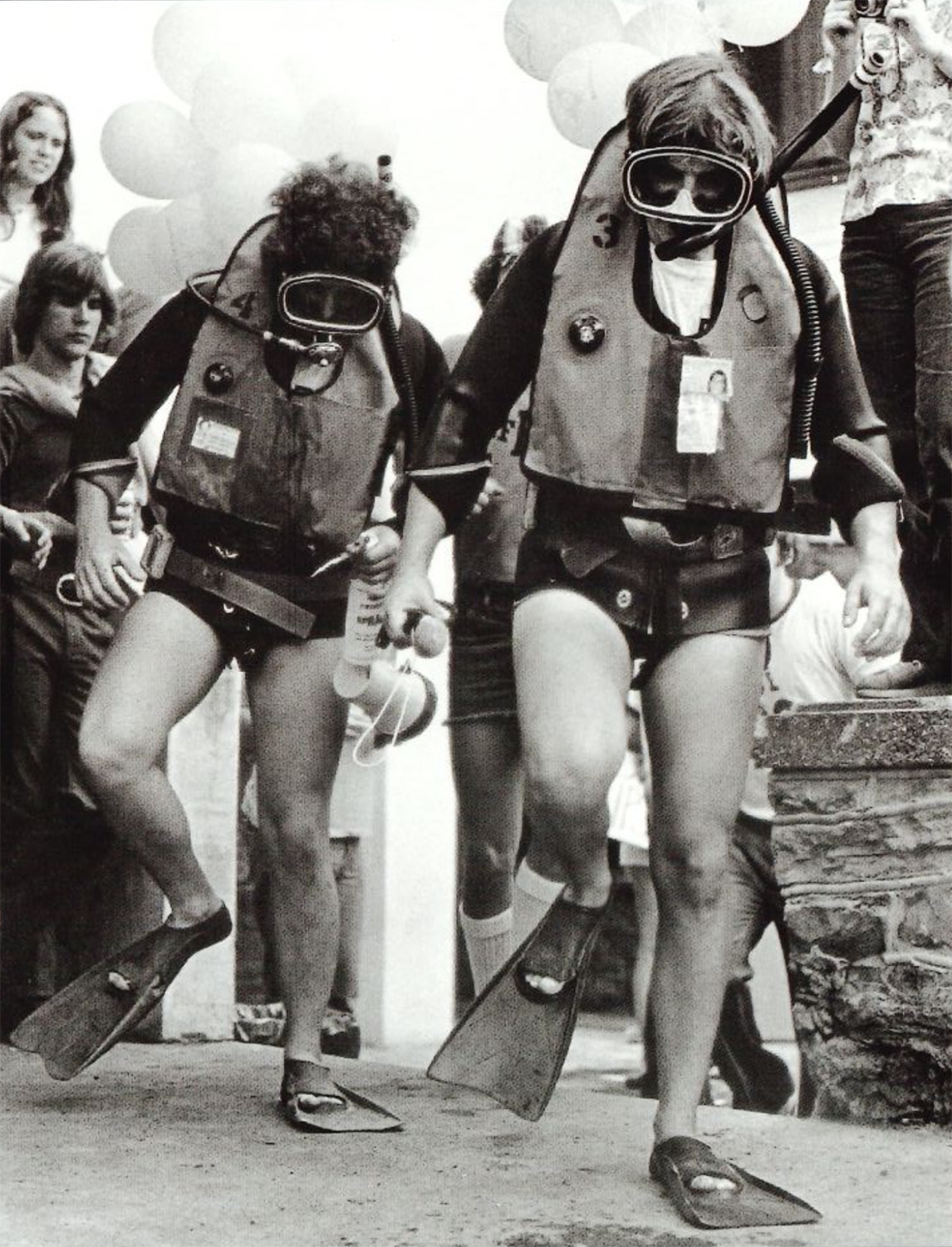 black and white photo of two students in scuba gear walking through downtown during a Phi Psi 500 by Penn State Archives